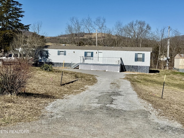 manufactured / mobile home with gravel driveway and a wooden deck