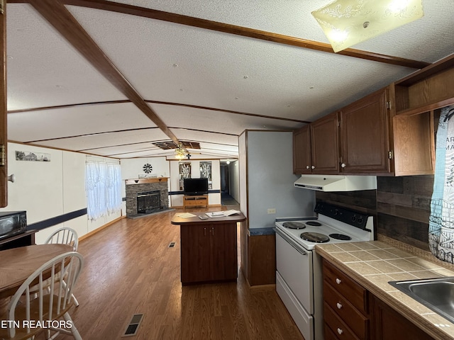 kitchen with a fireplace, tile counters, electric range, dark wood-type flooring, and under cabinet range hood