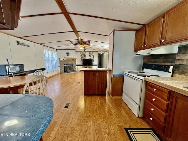 kitchen with white electric range oven, light wood finished floors, open floor plan, under cabinet range hood, and a fireplace