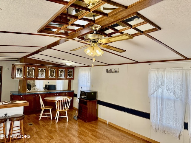 bar with lofted ceiling with beams, ceiling fan, a textured ceiling, light wood-type flooring, and black microwave