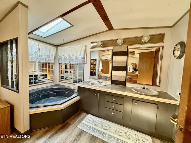 full bathroom featuring double vanity, lofted ceiling with skylight, a sink, and wood finished floors