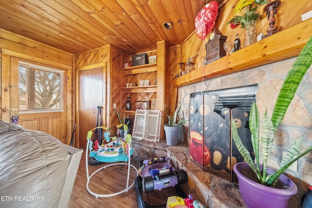 living room with built in shelves, a fireplace, wood walls, wood finished floors, and wooden ceiling