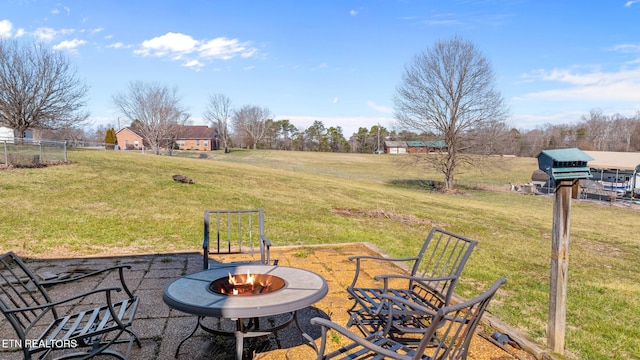 view of patio with a rural view, fence, a fire pit, and area for grilling