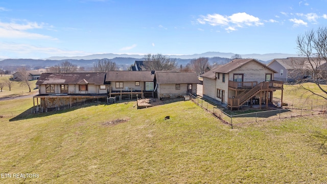 view of yard with a deck with mountain view, stairs, and fence