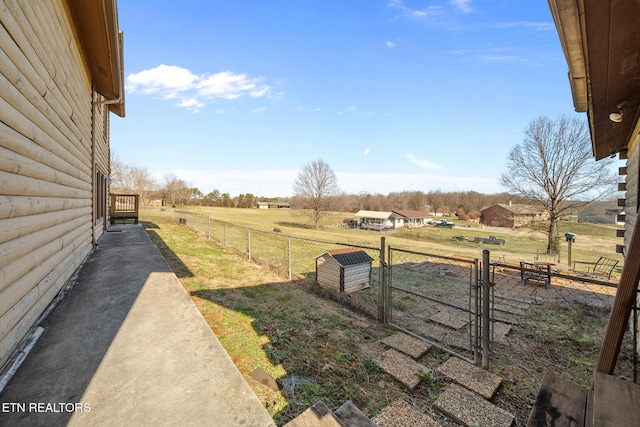 view of yard featuring a rural view, fence, and a gate