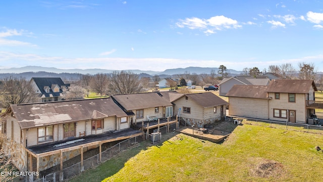 rear view of house featuring a fenced backyard, a mountain view, central air condition unit, a yard, and a residential view