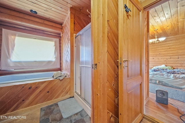 interior space featuring a stall shower, wood ceiling, wooden walls, and an inviting chandelier