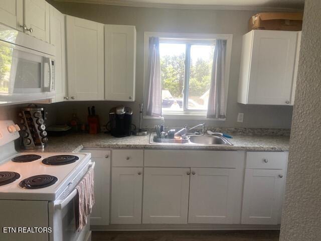 kitchen with light countertops, white appliances, white cabinetry, and a sink