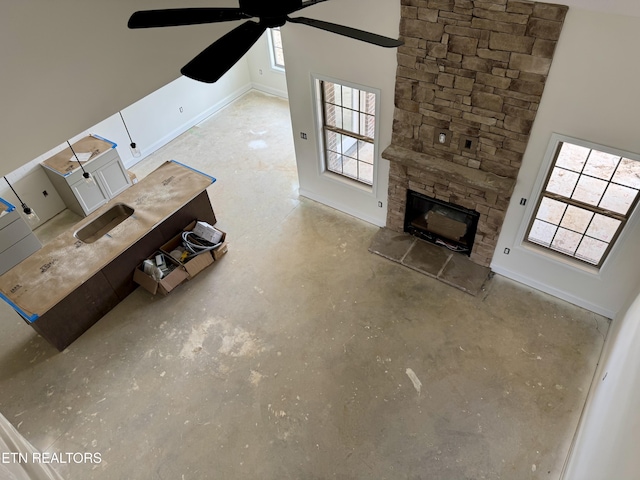 2127 Lantern Park Ln, Knoxville, TN 37932 - unfurnished living room featuring concrete floors, a ceiling fan, plenty of natural light, and a stone fireplace