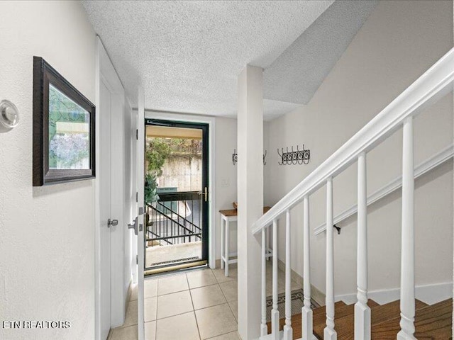 foyer with stairway, a textured ceiling, and light tile patterned flooring