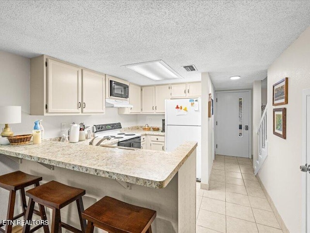 kitchen with electric range oven, freestanding refrigerator, a peninsula, light countertops, and black microwave