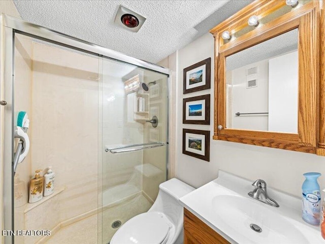 full bath with a textured ceiling, vanity, a shower stall, and toilet