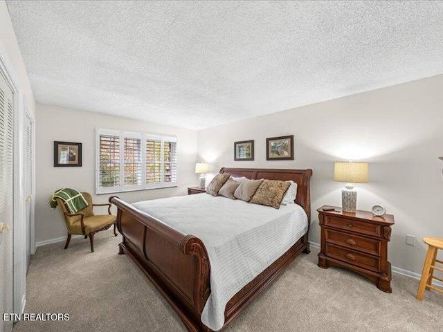 bedroom featuring light carpet, baseboards, and a textured ceiling