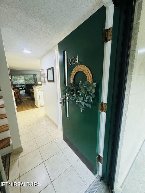 hallway featuring light tile patterned floors, stairway, and a textured ceiling