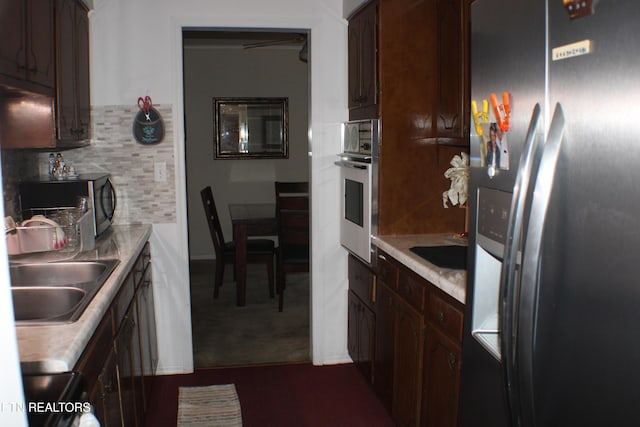 kitchen with dark brown cabinetry, tasteful backsplash, appliances with stainless steel finishes, light countertops, and a sink