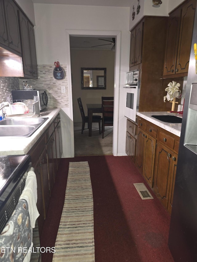 kitchen with light countertops, visible vents, backsplash, a sink, and oven