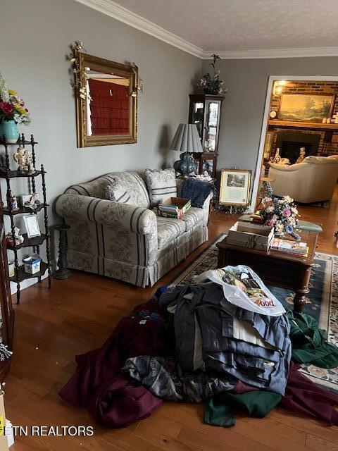 living area with ornamental molding, wood finished floors, and heating unit