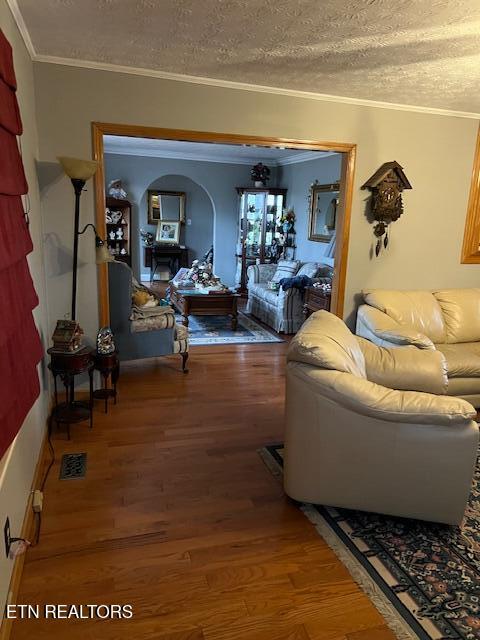 living area featuring crown molding, a textured ceiling, and wood finished floors