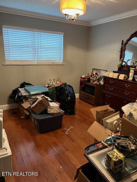 bedroom with baseboards, ornamental molding, and wood finished floors