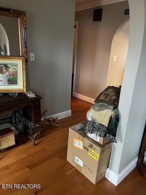 interior space featuring arched walkways, wood finished floors, and baseboards