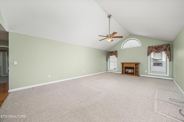 unfurnished living room with baseboards, carpet floors, lofted ceiling, ceiling fan, and a glass covered fireplace
