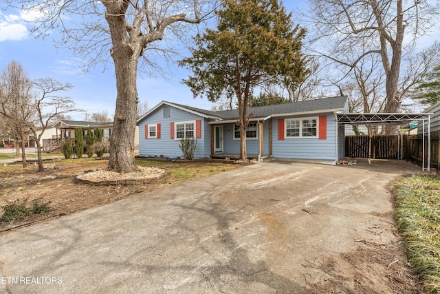 single story home with an attached carport, concrete driveway, and fence