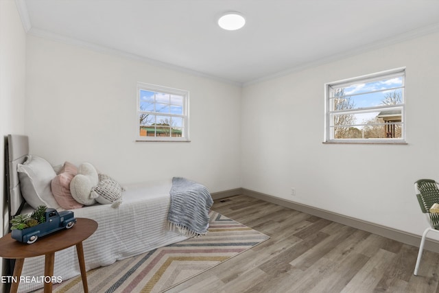 bedroom featuring wood finished floors, baseboards, multiple windows, and ornamental molding