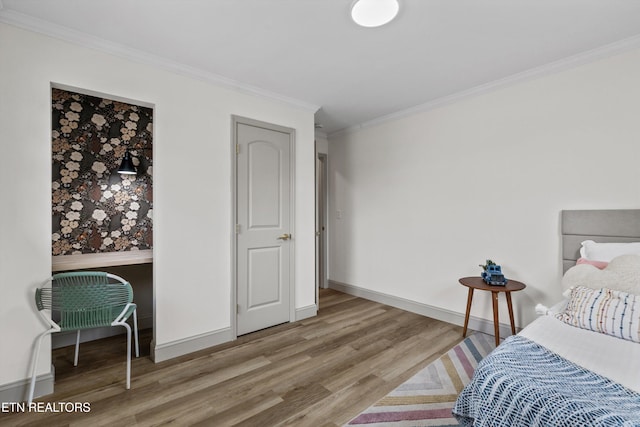 bedroom with wood finished floors, baseboards, and ornamental molding