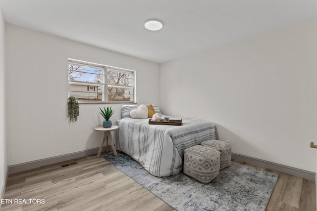 bedroom with visible vents, baseboards, and wood finished floors