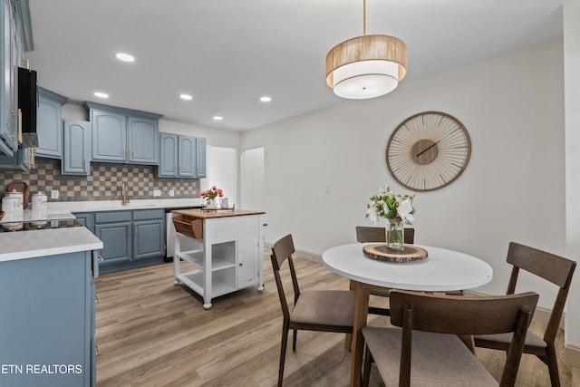 kitchen featuring tasteful backsplash, blue cabinetry, light wood-type flooring, and open shelves