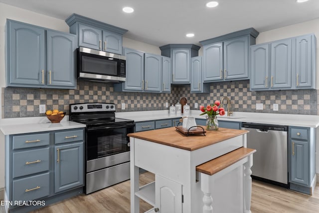 kitchen featuring butcher block countertops, blue cabinetry, and appliances with stainless steel finishes