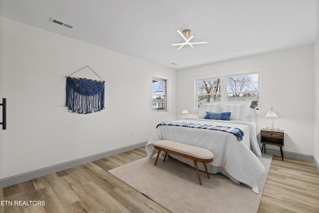 bedroom with visible vents, baseboards, and light wood finished floors