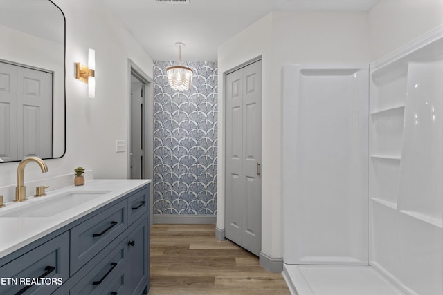 bathroom with a closet, a notable chandelier, wood finished floors, and vanity