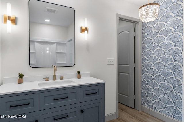 bathroom featuring visible vents, vanity, an inviting chandelier, and wood finished floors