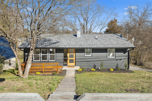 view of front facade with a chimney, a front lawn, roof with shingles, and a porch