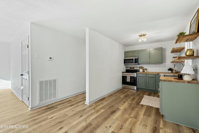 kitchen featuring visible vents, green cabinets, appliances with stainless steel finishes, wood counters, and open shelves