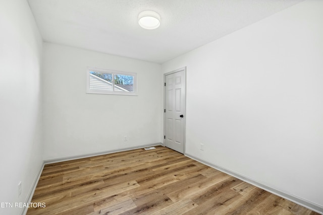 empty room featuring baseboards and light wood-style floors