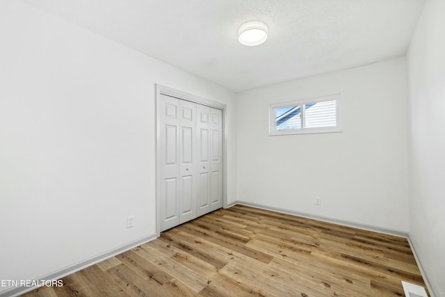 unfurnished bedroom with a closet, visible vents, baseboards, and light wood-style floors