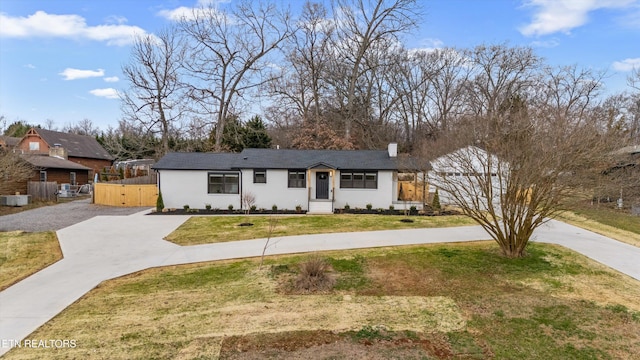 ranch-style home featuring stucco siding, a front lawn, a gate, fence, and concrete driveway