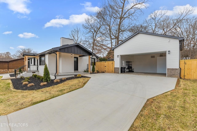 view of property exterior with driveway, a gate, fence, board and batten siding, and brick siding