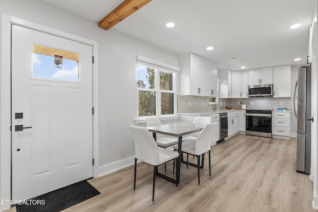 dining room with beam ceiling, recessed lighting, and light wood-style floors