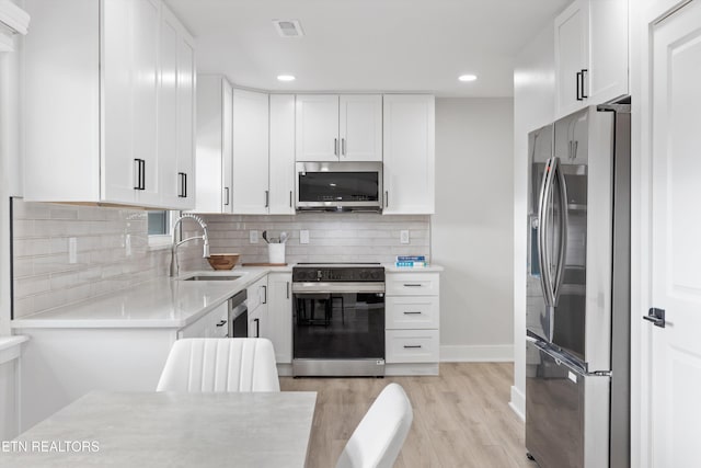 kitchen featuring tasteful backsplash, visible vents, light countertops, appliances with stainless steel finishes, and a sink