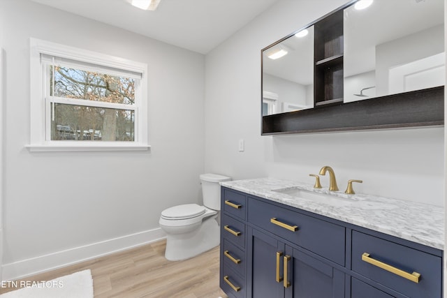 bathroom featuring toilet, vanity, baseboards, and wood finished floors