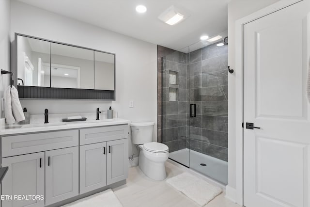 bathroom featuring double vanity, a stall shower, toilet, and a sink