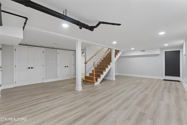 finished basement featuring recessed lighting, stairs, light wood-type flooring, and baseboards