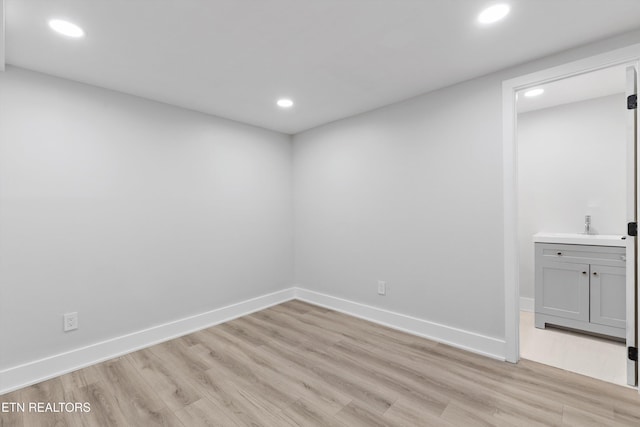 interior space featuring recessed lighting, baseboards, light wood finished floors, and a sink