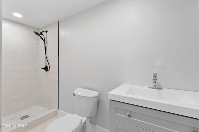 bathroom featuring vanity, toilet, and a tile shower