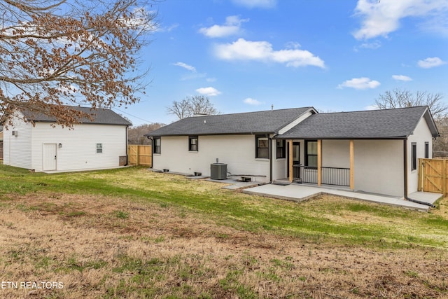 back of house featuring a lawn, fence, central AC, and a shingled roof