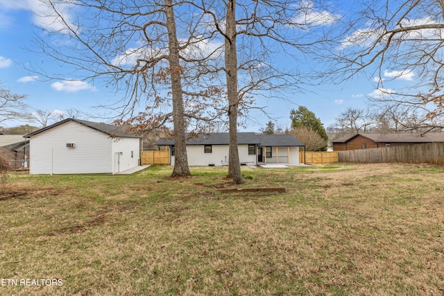 rear view of house featuring an outbuilding, a patio, a yard, and fence