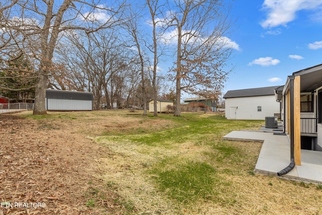 view of yard featuring an outbuilding, central AC unit, fence, a storage unit, and a patio area